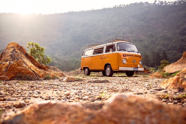 orange campervan parked in a rubbly, hilly area