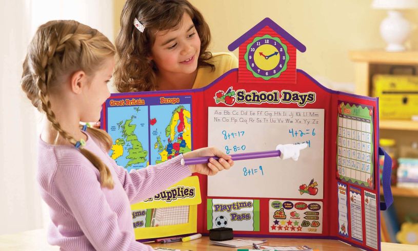 two young girls playing with the school role play set 