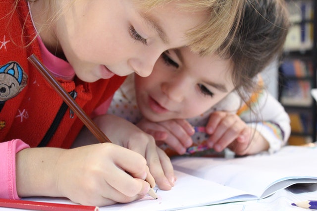 two children intensely studying a book