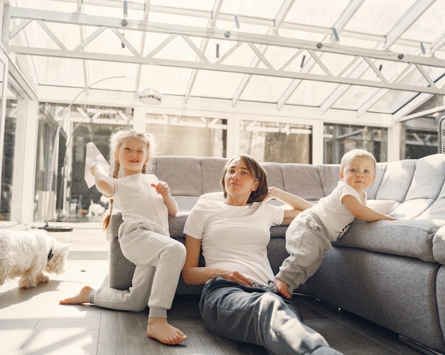 Mum and two children playing fun indoor game of paper planes