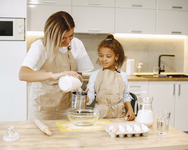 Mum and young daughter in kitchen baking together