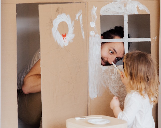 Dad and daughter painting a cardboard den for fun indoor games